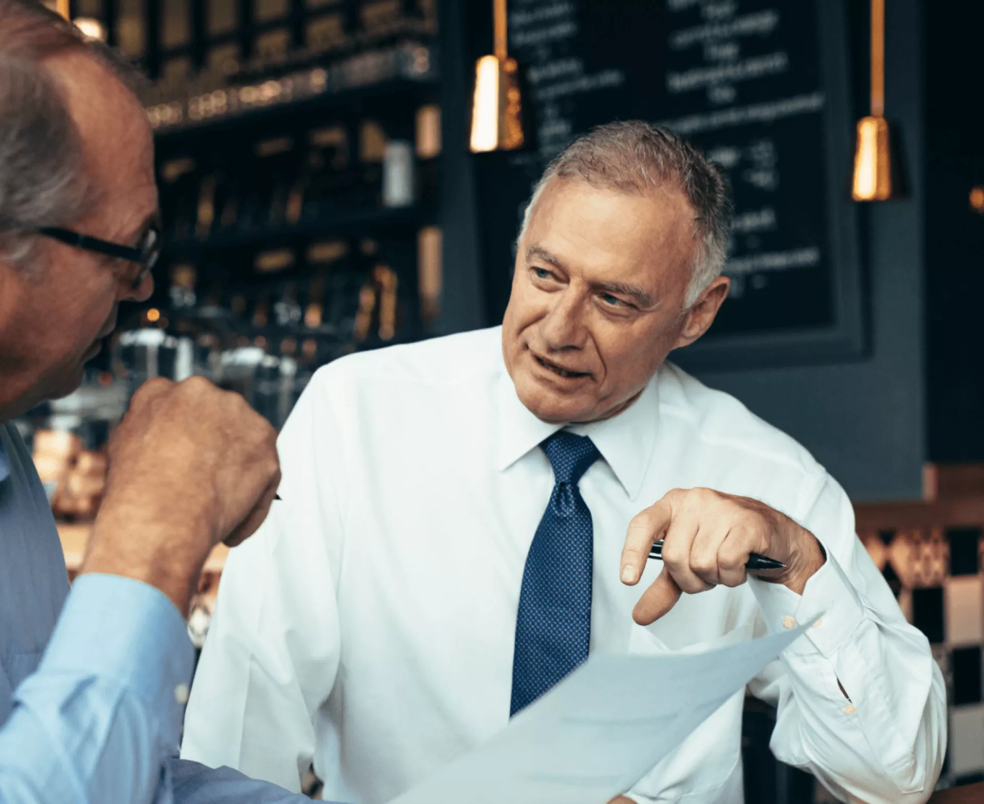 Twee mannen in gesprek in een café.