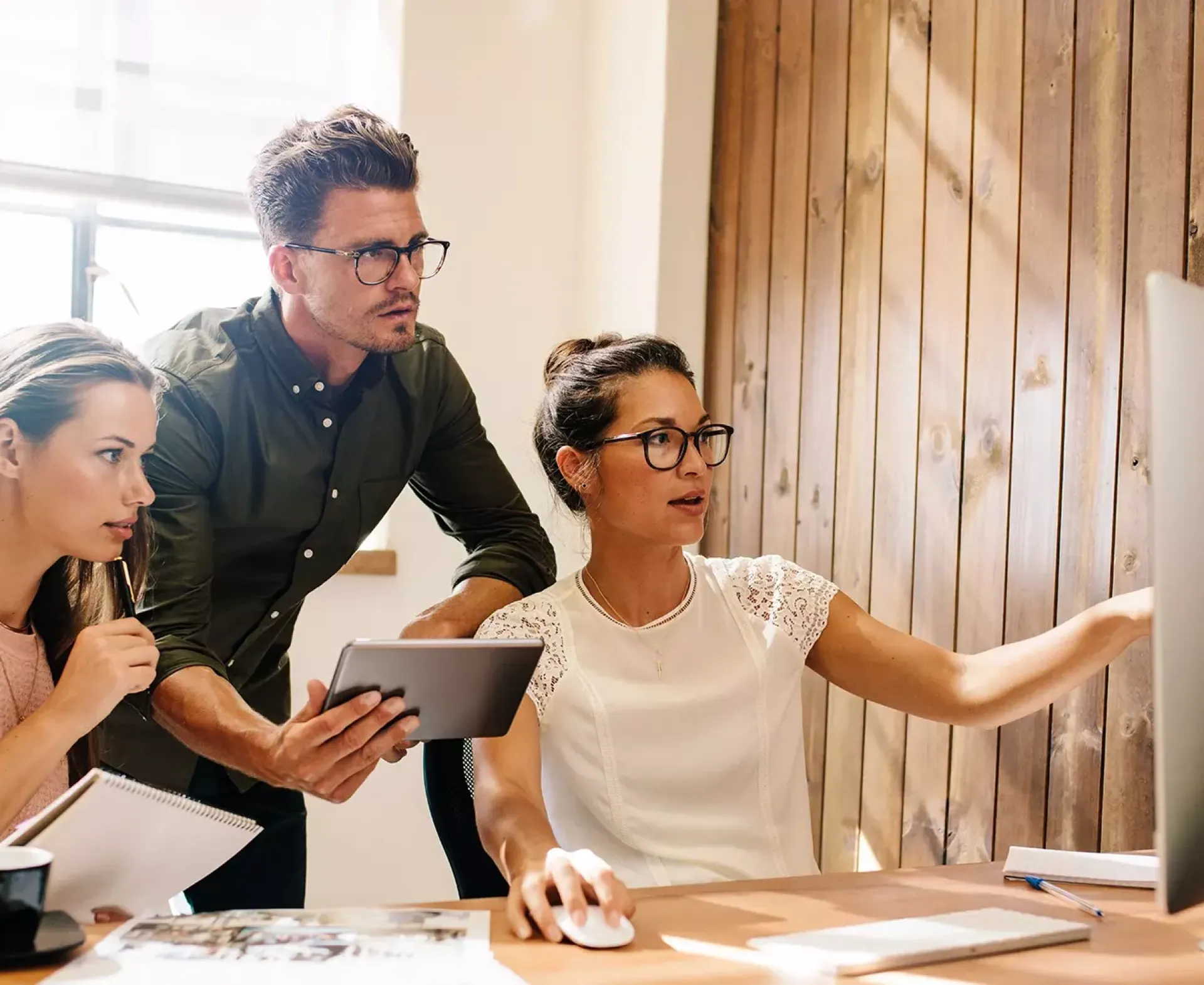 Drie mensen die samenwerken aan een computerproject.