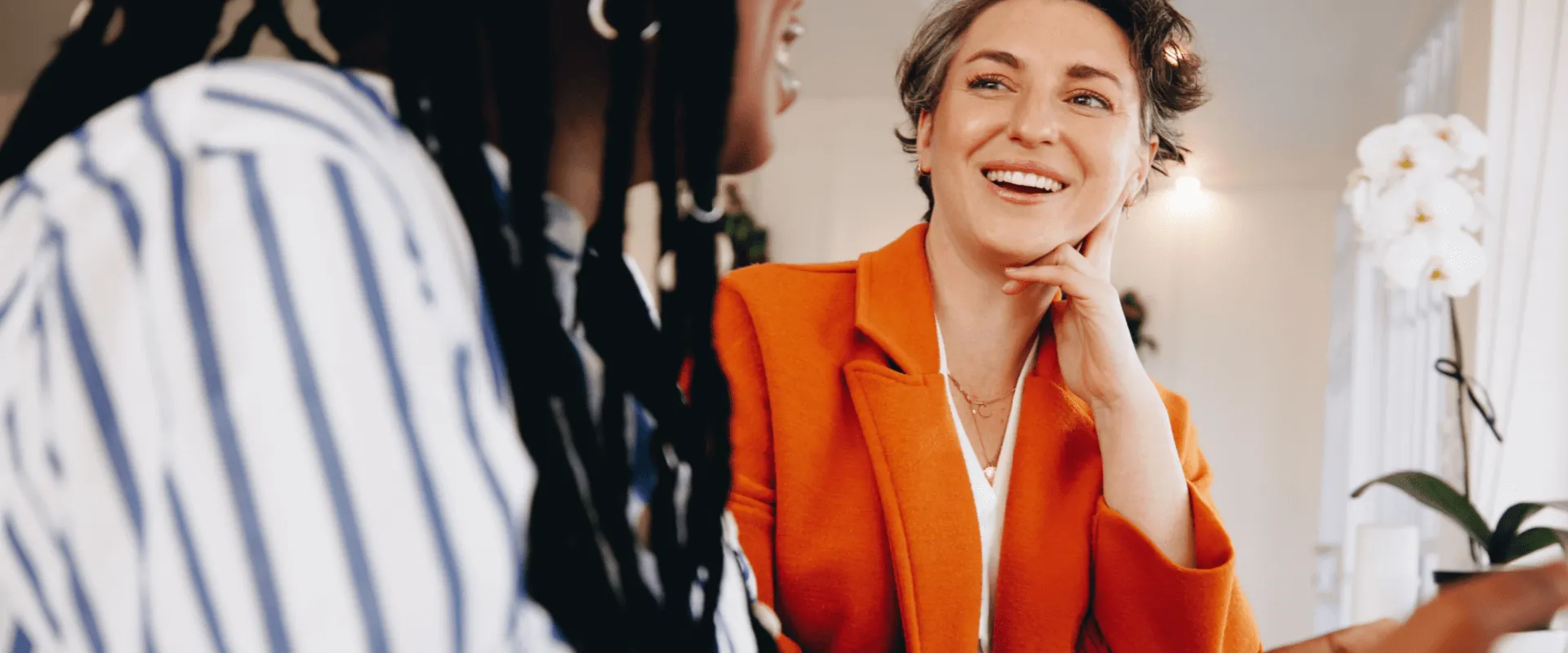 Twee vrouwen in een gesprek, glimlachend en ontspannen.