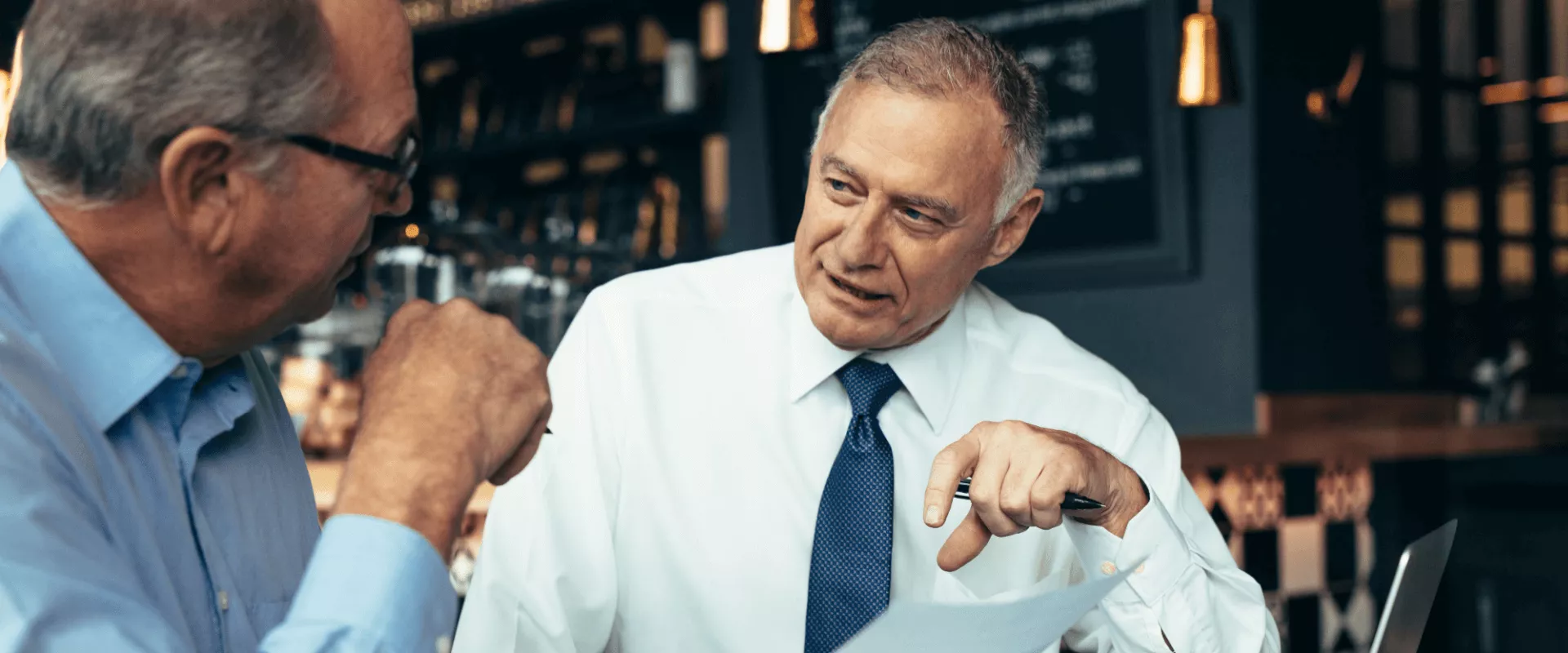 Twee mannen in gesprek in een café.
