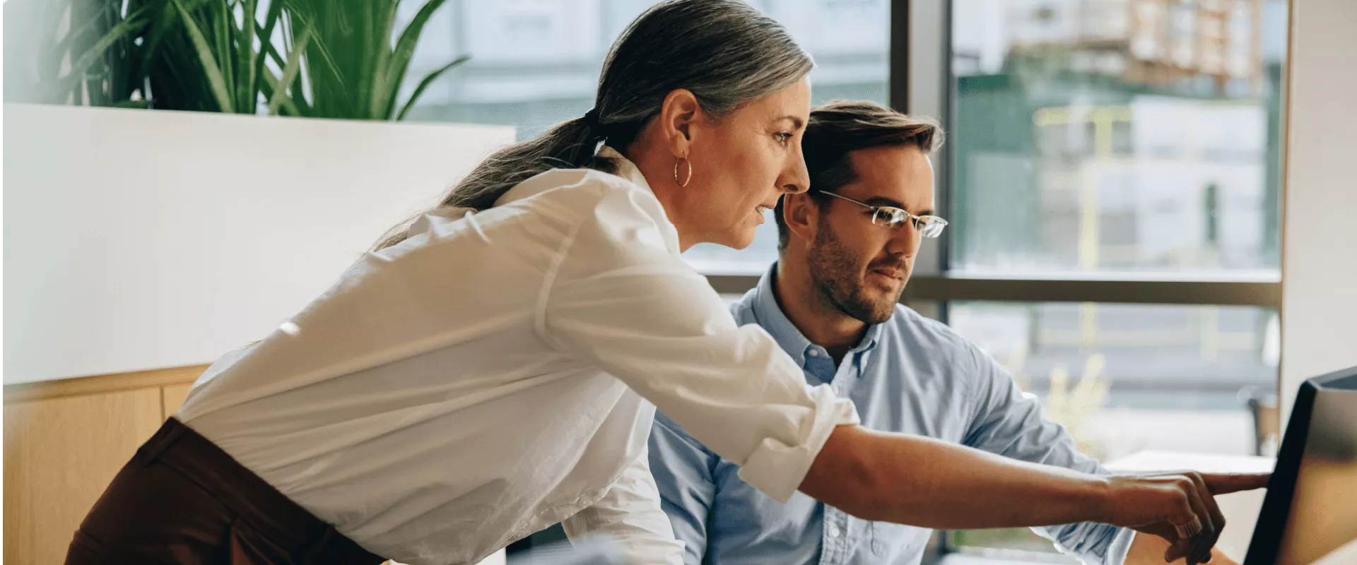 Twee collega's werken samen aan een computer.