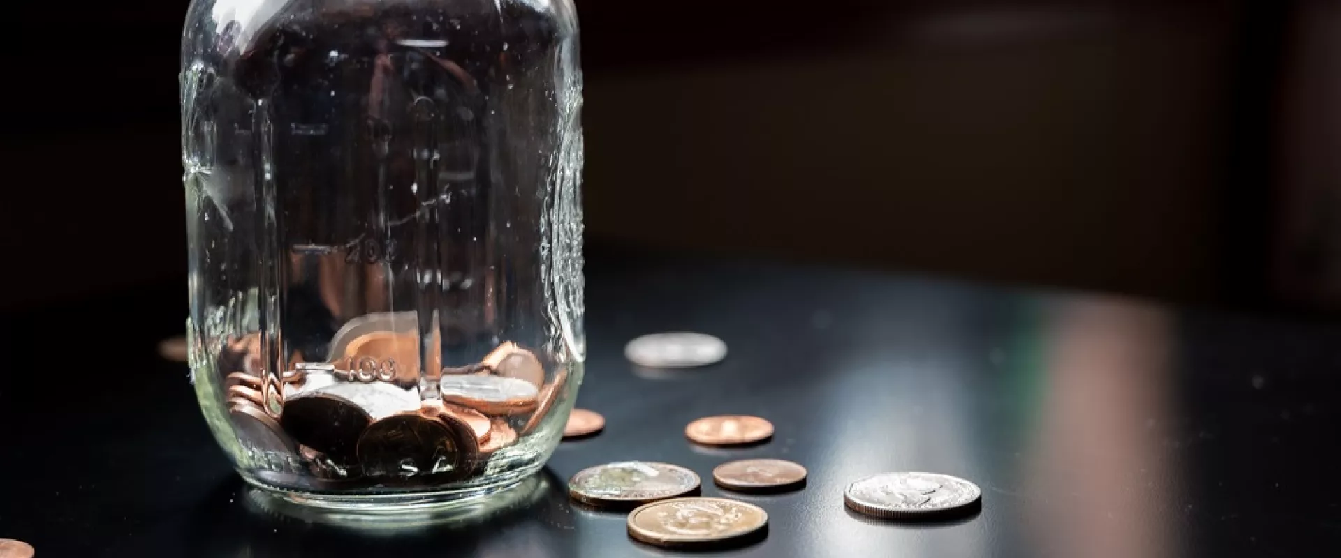 Een glazen pot gevuld met munten op een tafel.