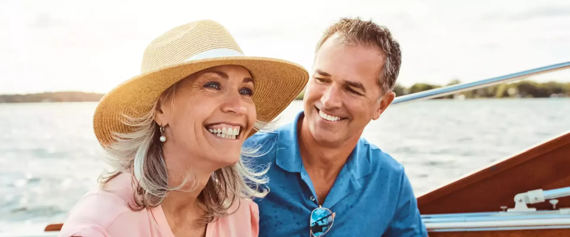 Een lachend stel op een boot geniet van een zonnige dag op het water.