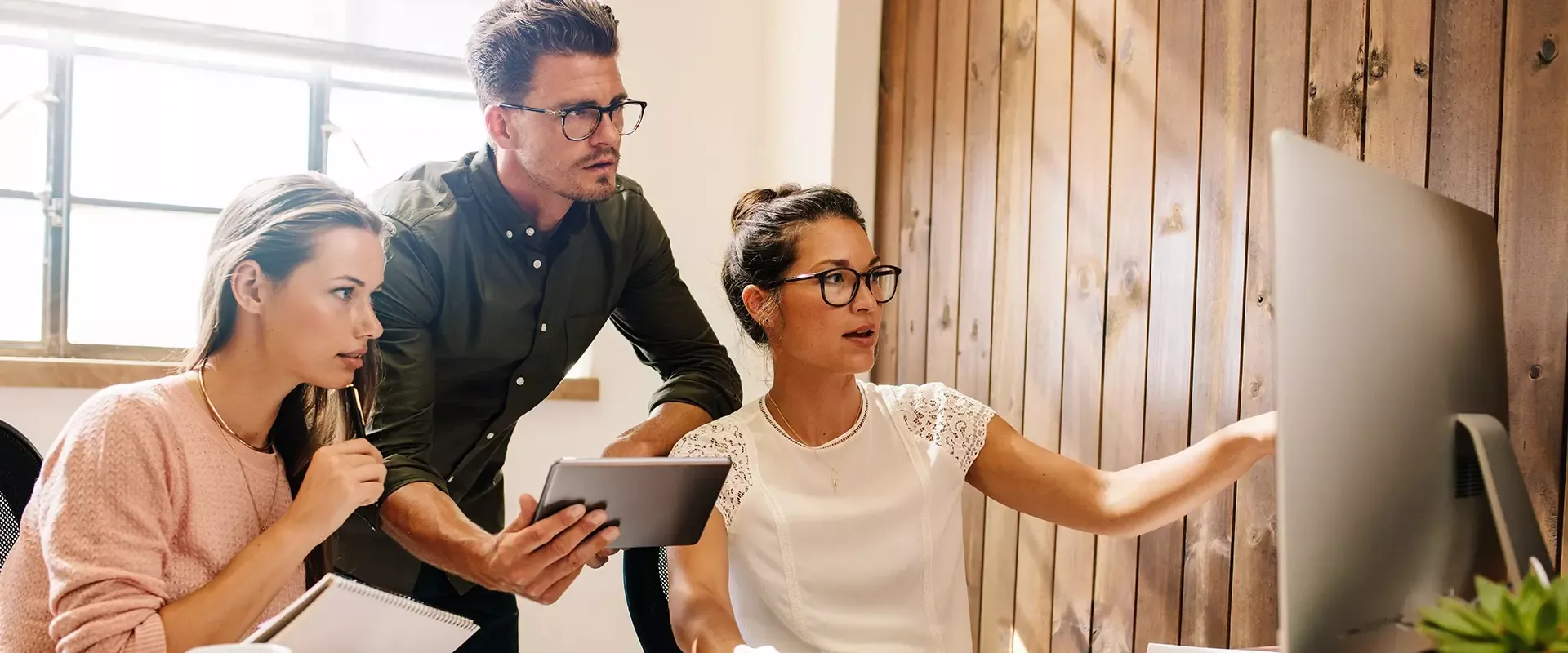 Drie mensen die samenwerken aan een computerproject.