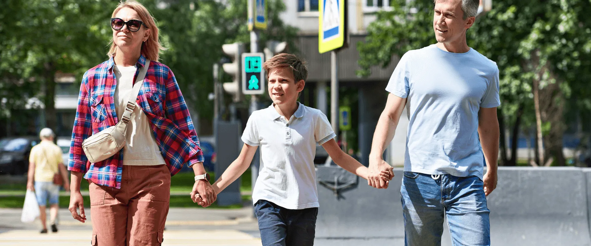 Een gezin steekt hand in hand een straat over op een zonnige dag.