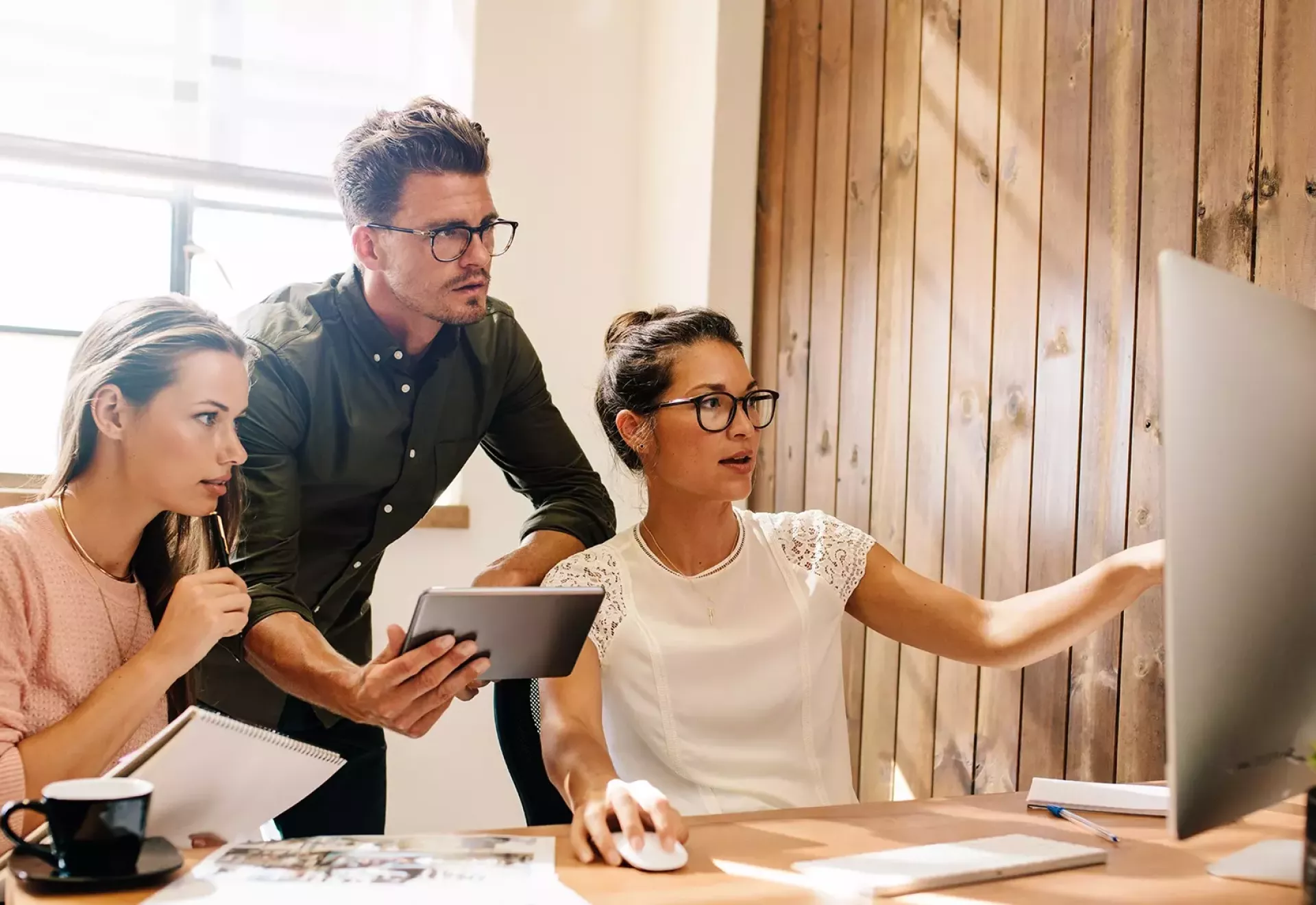 Drie mensen die samenwerken aan een computerproject.