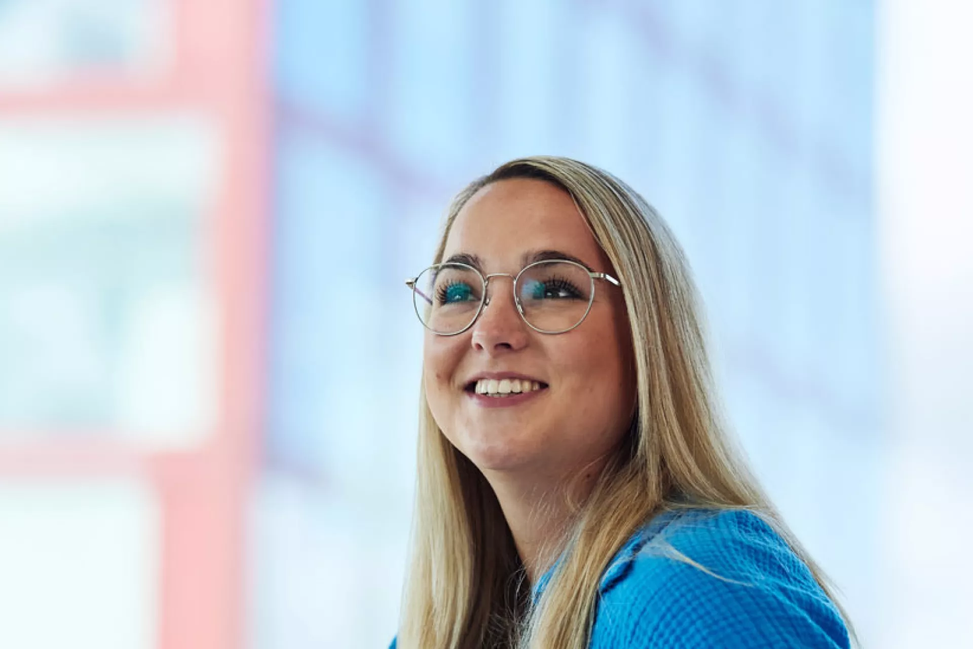 Een vrouw met een bril glimlacht tijdens een gesprek.