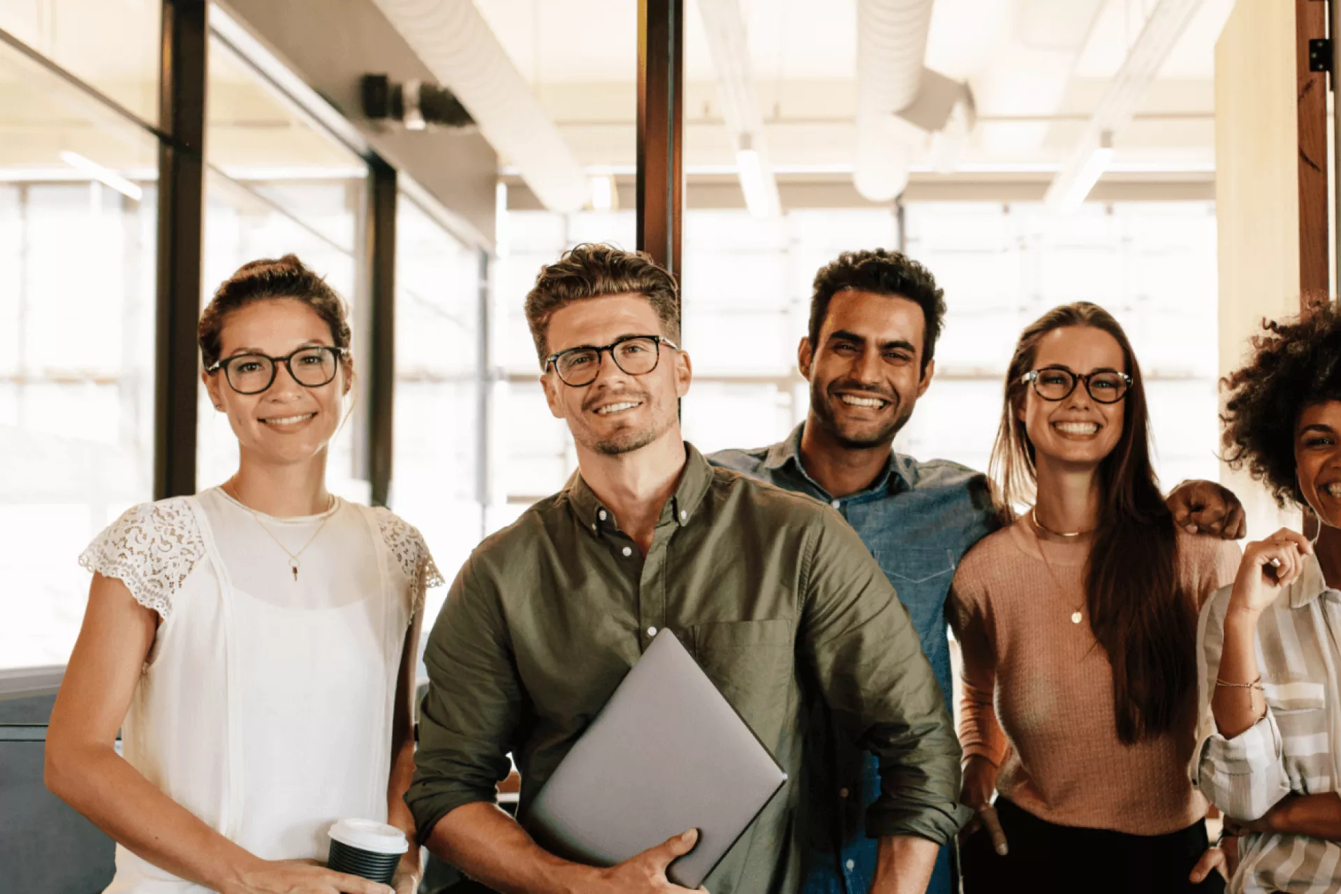 Een groep collega's poseert samen in een modern kantoor.