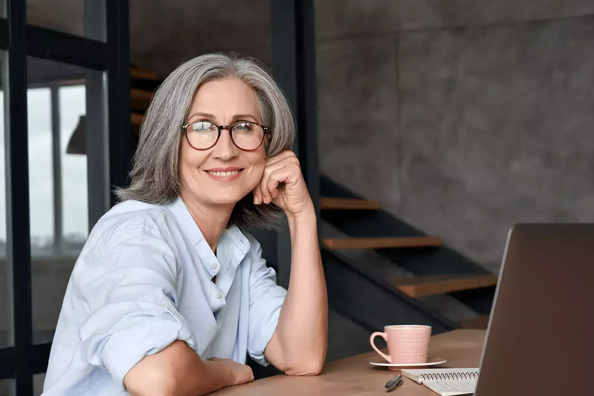 Vrouw werkt glimlachend op een laptop in een modern kantoor.