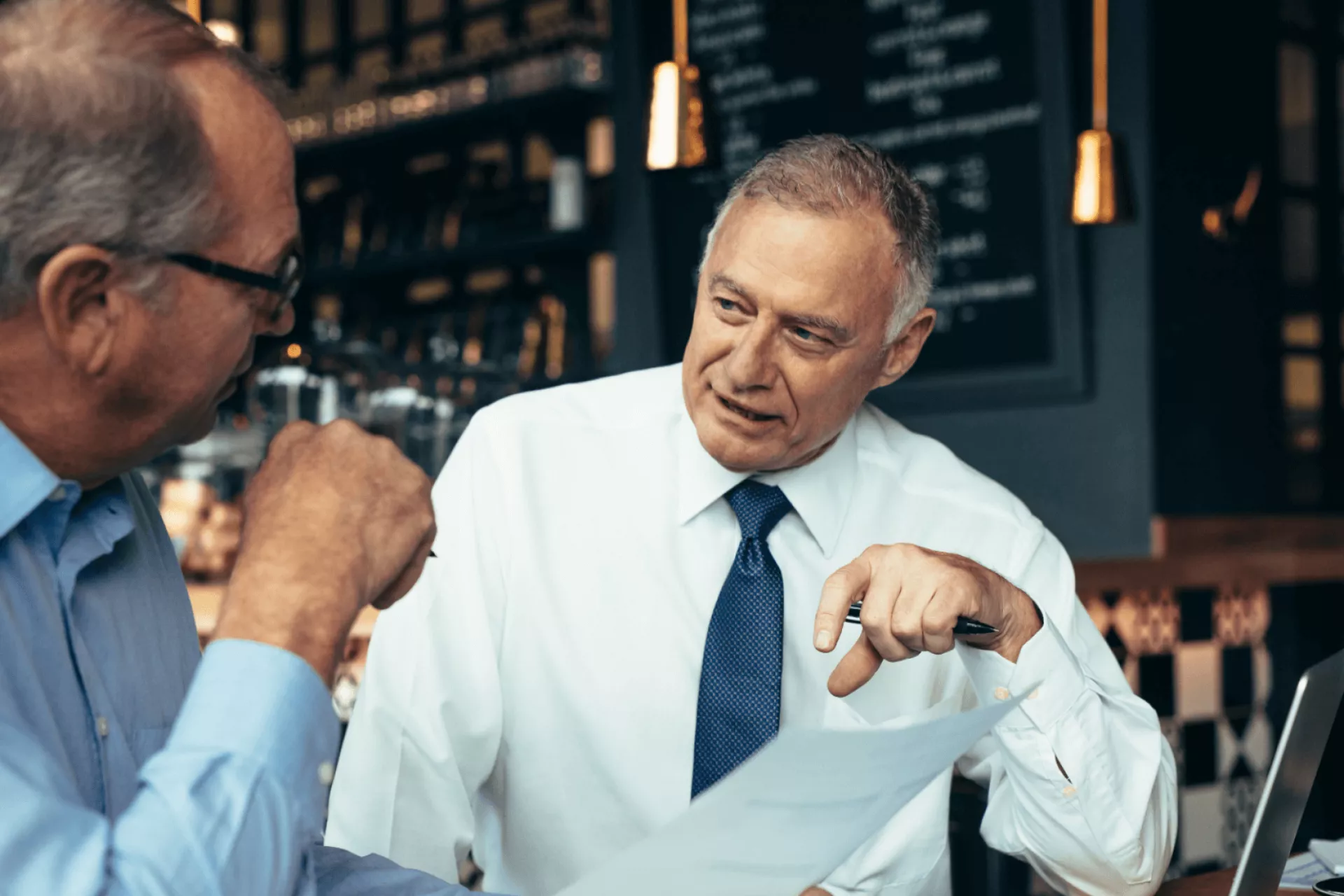 Twee mannen in gesprek in een café.