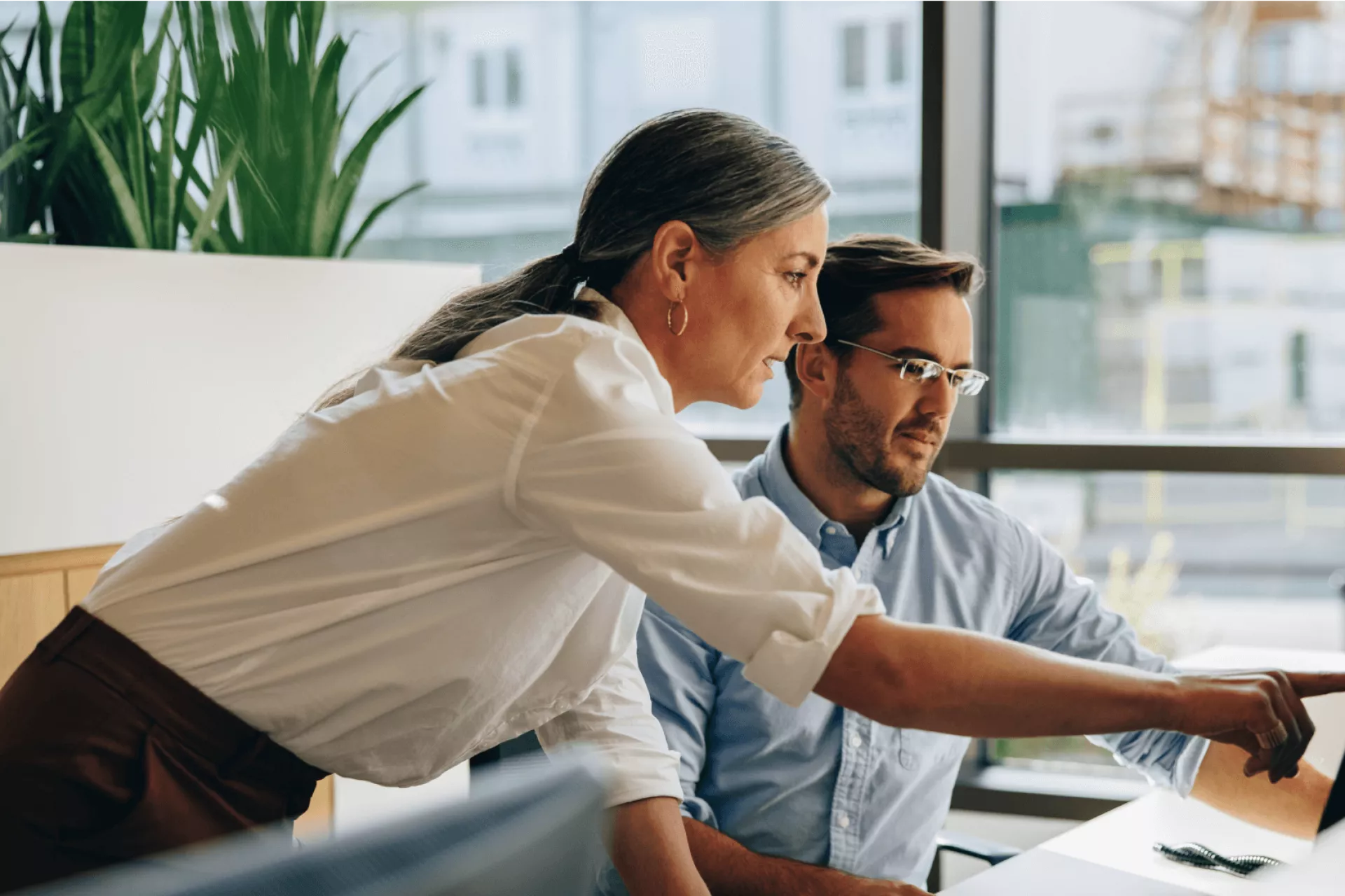 Twee collega's werken samen aan een computer.