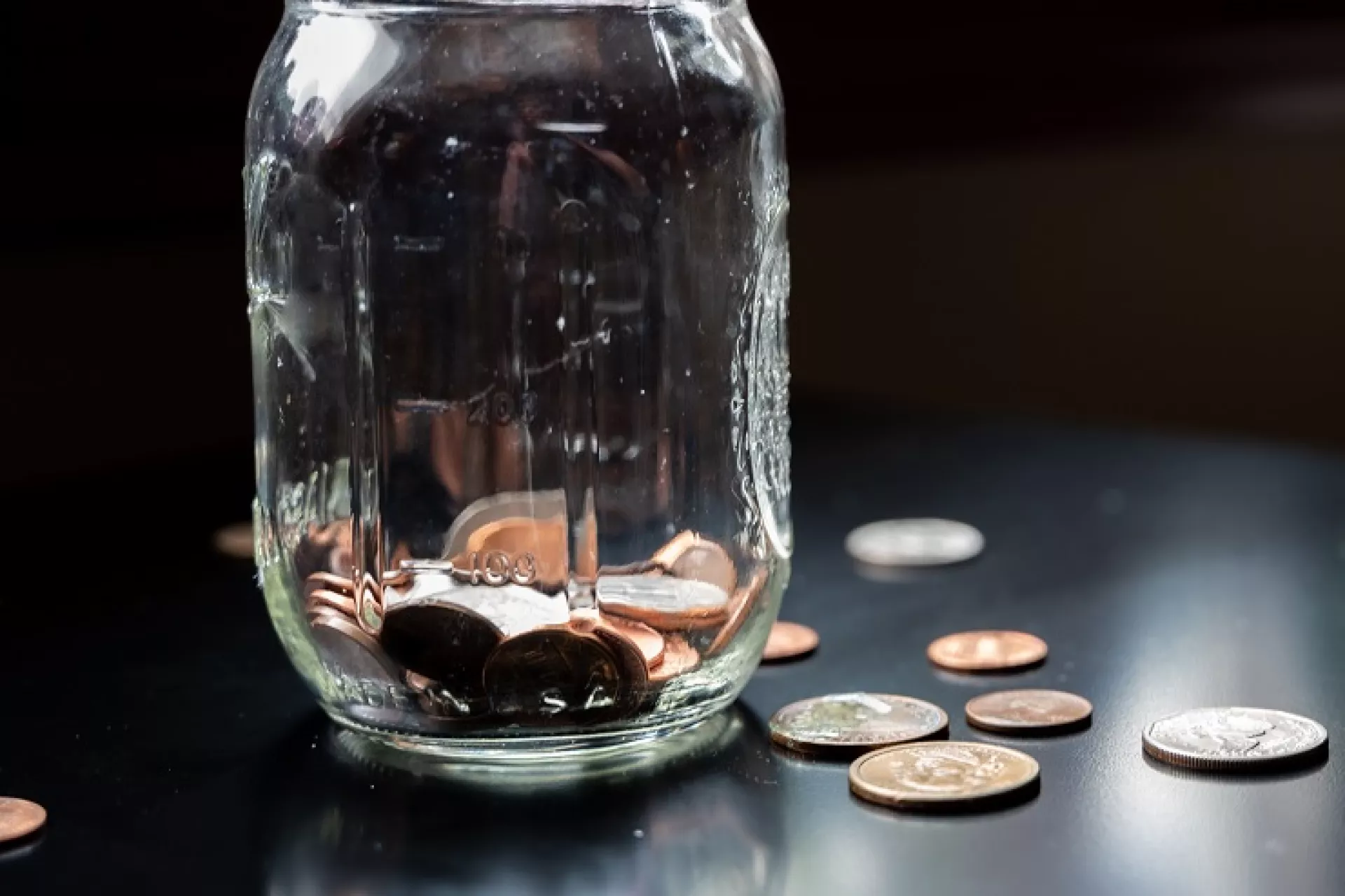 Een glazen pot gevuld met munten op een tafel.